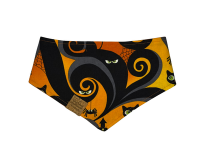 A triangular pet bandana featuring a Halloween-themed print with a large black cat silhouette, orange swirls, spiderwebs, spiderbugs, and cat faces on a bright orange background.